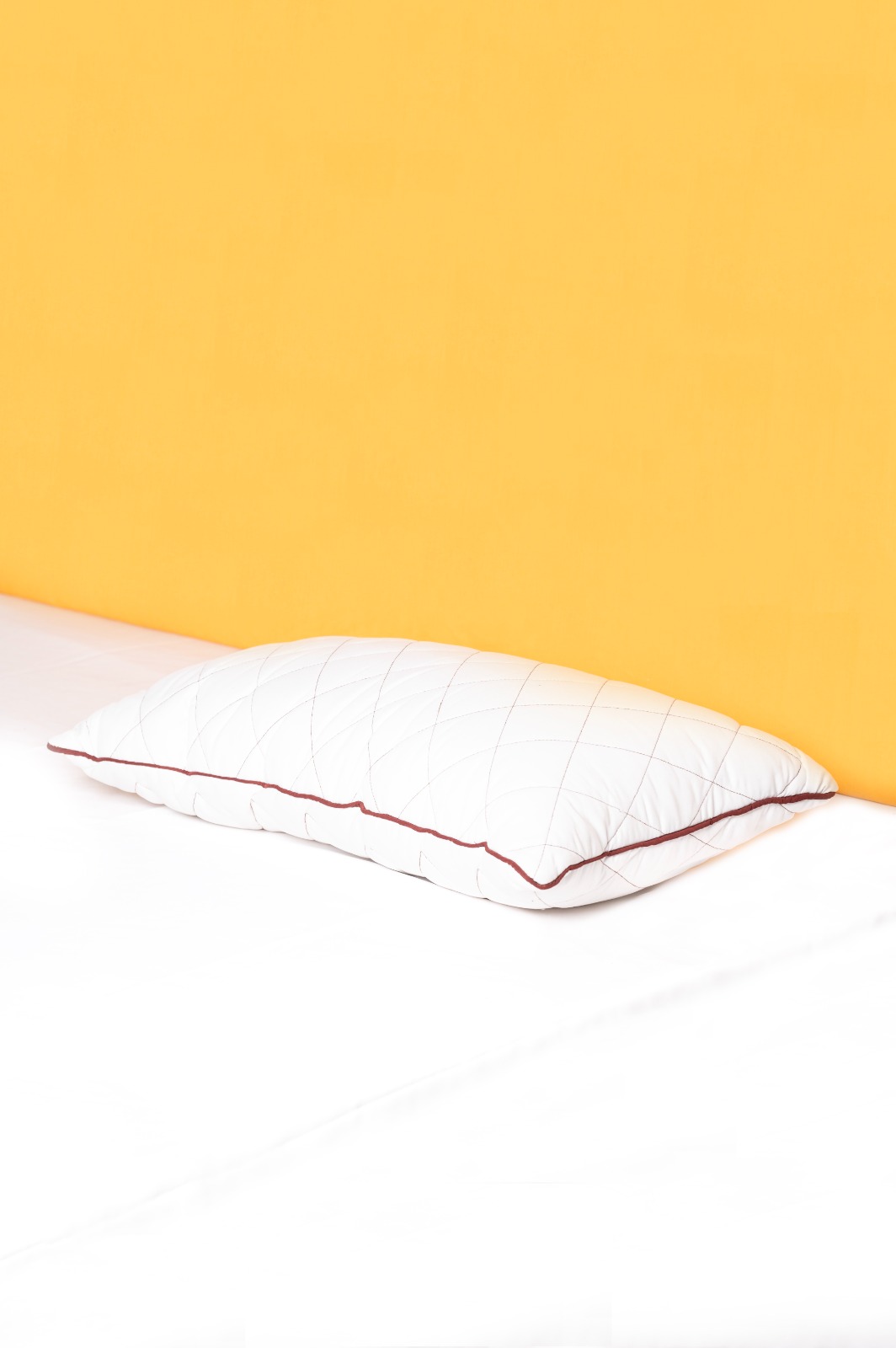 Quilted pillow with maroon piping